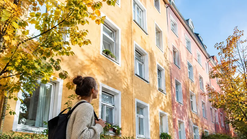 Bunte sanierte Fassade eines Mehrfamilienhauses mit vielen weißen Fenstern, von denen einige gekippt sind